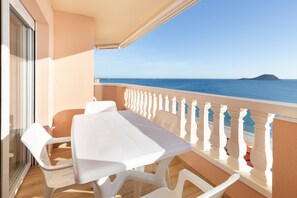 A balcony with a table and chairs, a railing, and a view of the sea. - Apartment 'Isla Grosa' with Sea Views, Wi-Fi and Air Conditioning (La Manga del Mar Menor)