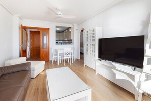A living room with a sofa, a coffee table, a TV, and a kitchen in the background. - Apartment 'Isla Grosa' with Sea Views, Wi-Fi and Air Conditioning (La Manga del Mar Menor)