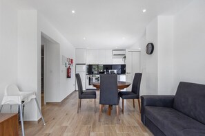 A modern kitchen with white cabinets, a dining table with chairs, and a black sofa. - Holiday Home 'Refugio Das Vinhas' with Mountain View, Wi-Fi and Air Conditioning (Celorico de Basto)