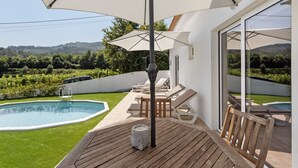 A poolside area with a wooden deck, lounge chairs, and a large umbrella. - Holiday Home 'Refugio Das Vinhas' with Mountain View, Wi-Fi and Air Conditioning (Celorico de Basto)
