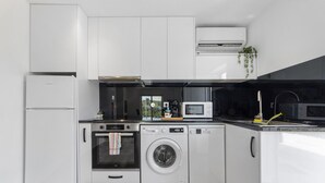 A compact kitchen with a refrigerator, oven, microwave, and dishwasher. - Holiday Home 'Refugio Das Vinhas' with Mountain View, Wi-Fi and Air Conditioning (Celorico de Basto)