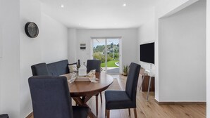 A modern dining area with a round table, chairs, a clock, and a TV on the wall. - Holiday Home 'Refugio Das Vinhas' with Mountain View, Wi-Fi and Air Conditioning (Celorico de Basto)
