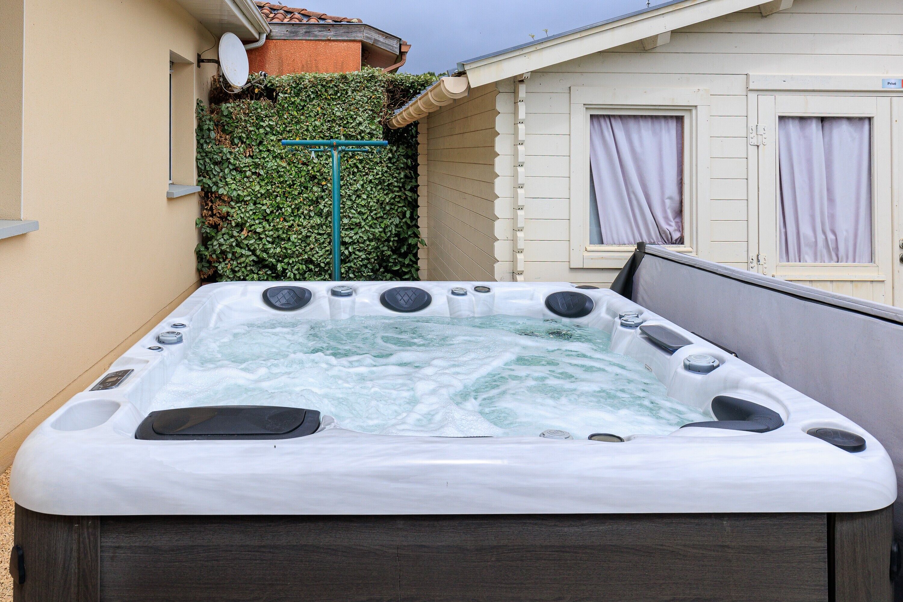 Un jacuzzi dans un jardin, avec une maison en arrière-plan.