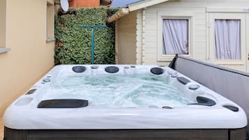 Un jacuzzi dans un jardin, avec une maison en arrière-plan.
