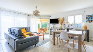A modern living room with a sofa, coffee table, and dining area with chairs and a table.