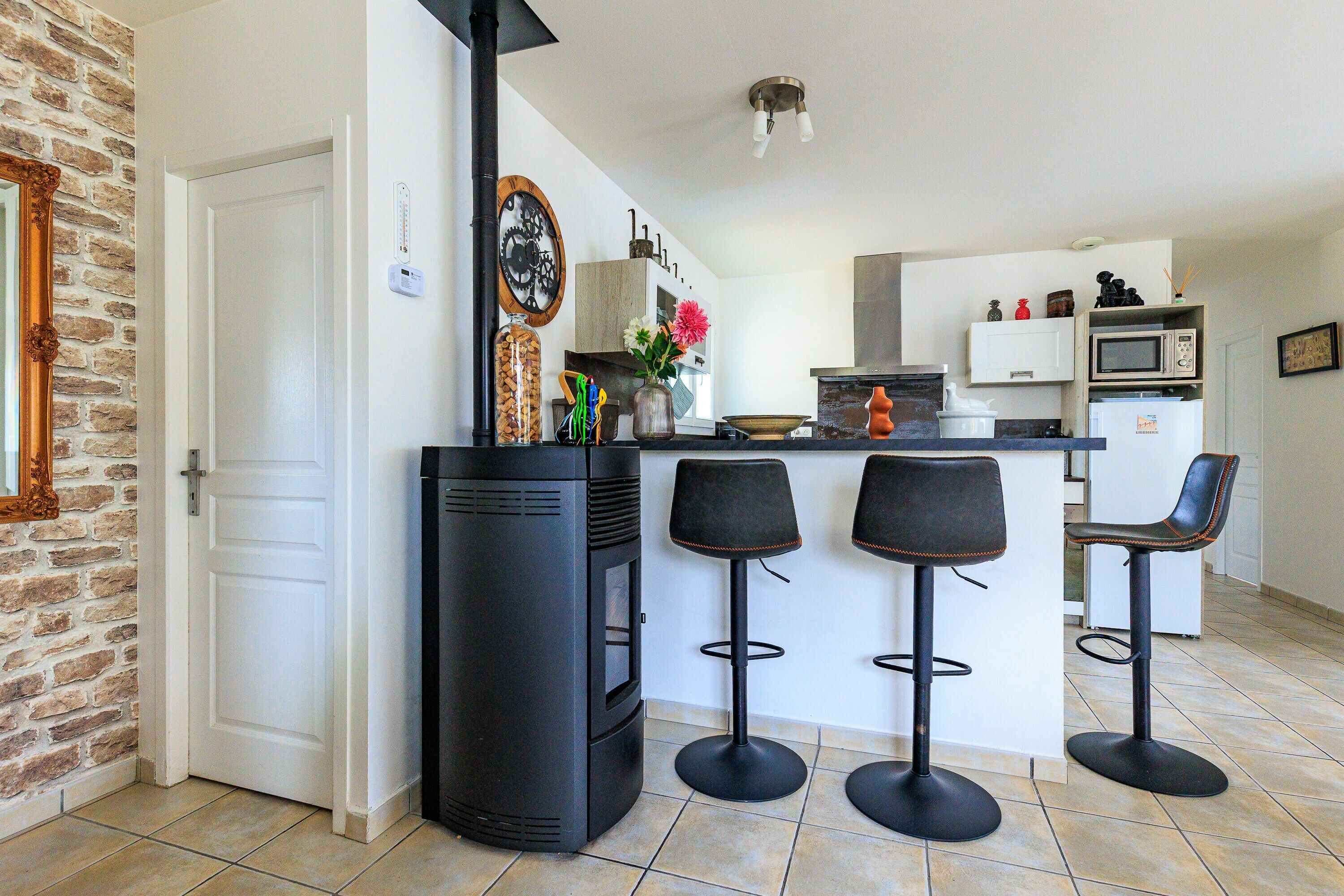 Une cuisine dotée d’un îlot central, de tabourets de bar, d’une cuisinière et d’un four à micro-ondes.