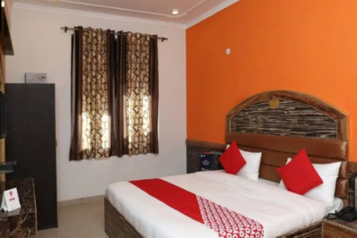A hotel room with a bed, a nightstand, a TV, and curtains.