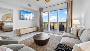 A modern living room with a sofa, coffee table, and a ceiling fan. - RIVER FLY IN: The Merritt, Launchpad Lookout View (Merritt Island)
