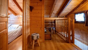 A wooden cabin interior with a bed, a bench, a window, and a staircase. - Chalet 'Chez Mémé' with Mountain View, Private Terrace and Private Garden (Hauteluce)