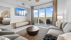 A modern living room with a sofa, coffee table, and a ceiling fan. - RIVER FLY IN: The Merritt, Launchpad Lookout View (Merritt Island)