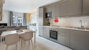 A modern kitchen with grey cabinets, a microwave, oven, and a dining area with a table and chairs.
