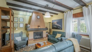 A cozy living room with a fireplace, a sofa, a coffee table, and a bookshelf. - Country House 'Ribera Del Duero' with Mountain View, Private Pool and Private Garden (TRASPINEDO)
