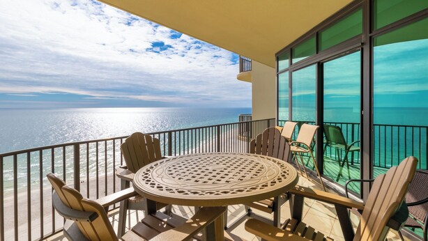 A balcony with a round table and chairs, overlooking a body of water. - Phoenix West 1506 (Orange Beach)