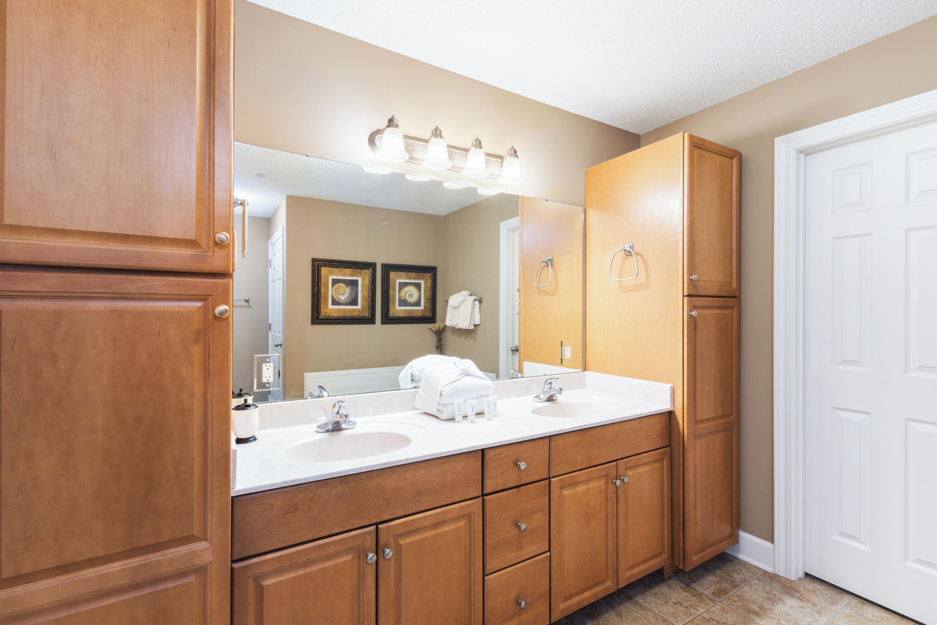 A bathroom with wooden cabinets, a double sink vanity, and a large mirror.