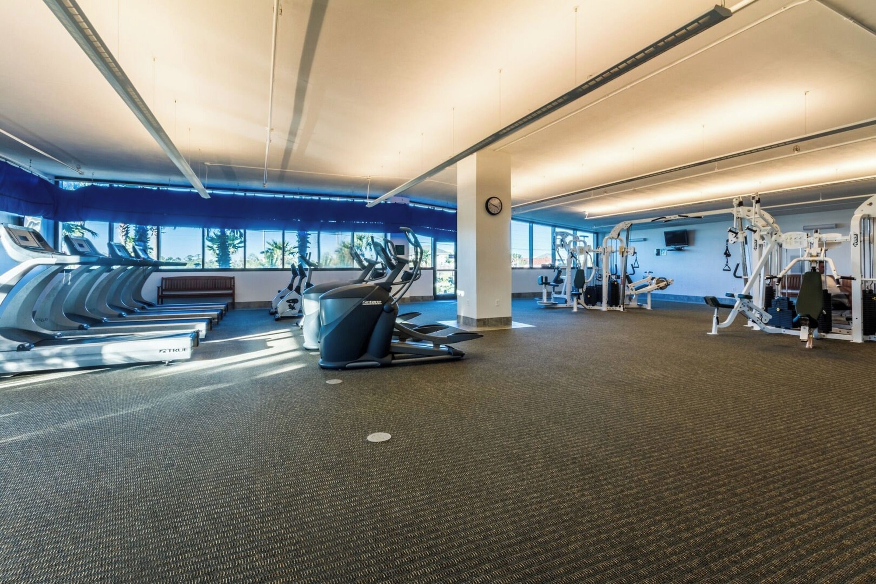 Un gimnasio con cintas de correr, elípticas y equipo de pesas.