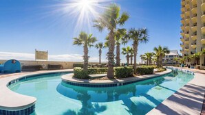 A swimming pool with palm trees and a building in the background. - Phoenix West 1506 (Orange Beach)