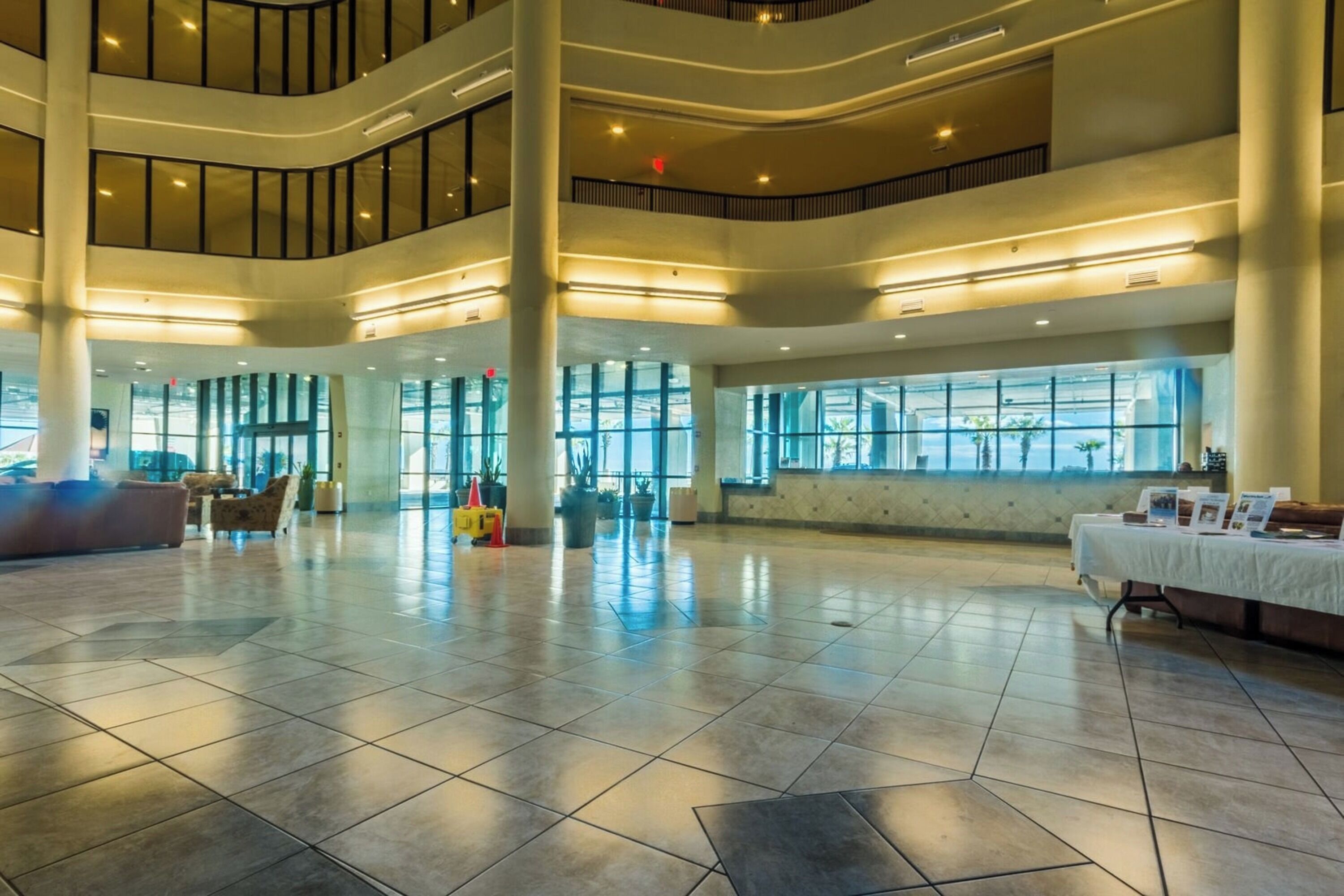 A spacious lobby with a high ceiling, large windows, and a central column.