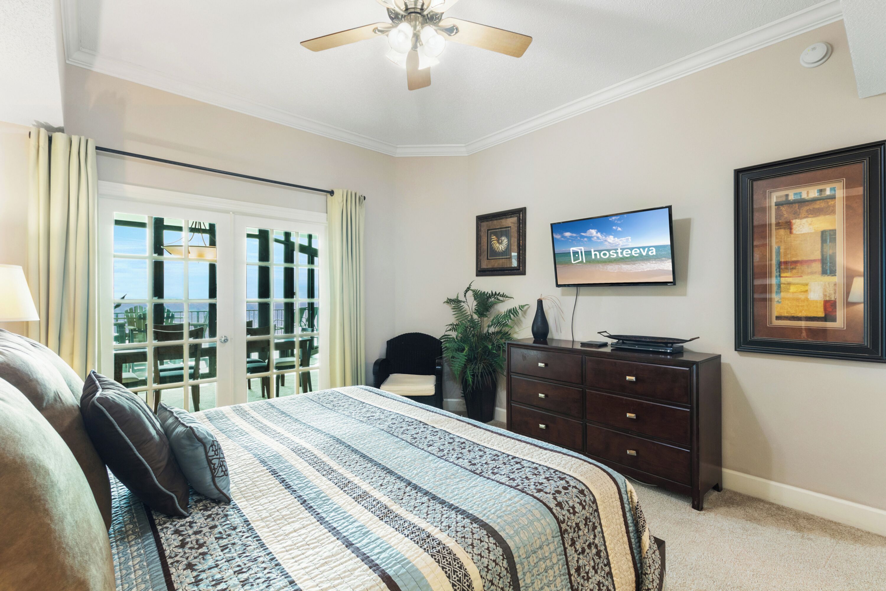 A bedroom with a bed, a dresser, a television, and a window with a view.