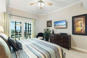 A bedroom with a bed, a dresser, a television, and a window with a view. - Phoenix West 1506 (Orange Beach)