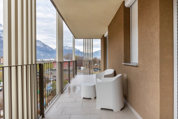 Un balcon avec vue sur les montagnes, une balustrade et deux chaises blanches.