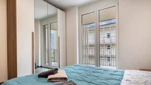 Een slaapkamer met een bed, een groot raam en een balkon.