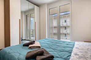 Une chambre à coucher avec un lit, une grande fenêtre et un balcon.
