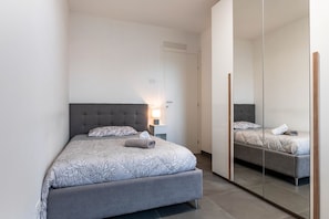 Une chambre à coucher avec un lit, une table de chevet, une lampe et un miroir.