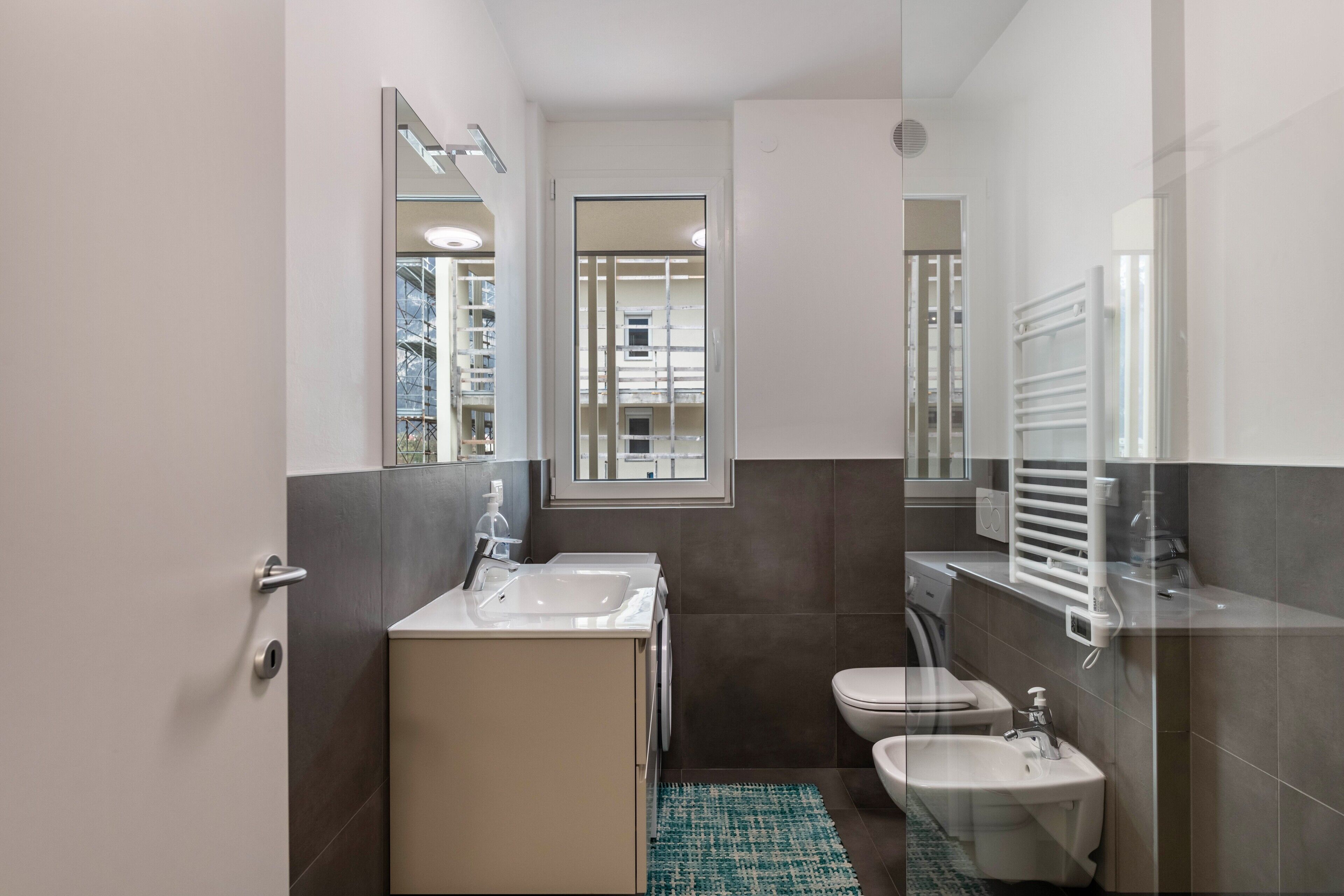 Un bany modern amb un lavabo, vàter, bidè i un mirall.