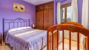 Un dormitorio con cama, armario de madera y ventana con cortinas.