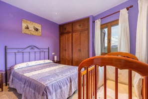 Una camera da letto con un letto, un'armadietto in legno e una finestra con tende.