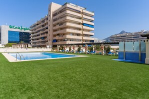 A hotel with a swimming pool, multiple balconies, and a view of a mountain.