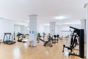 A gym with various exercise equipment, including treadmills, stationary bikes, and weight machines.