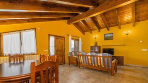 Un comedor con una mesa y sillas de madera, un sofá, un televisor y un cuadro en la pared.