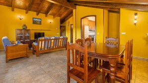 Un comedor con una mesa y sillas de madera, un sofá y una televisión.
