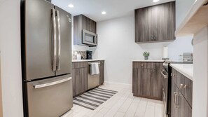 Une cuisine moderne équipée d’un réfrigérateur en acier inoxydable, d’un four à micro-ondes et de meubles de rangement en bois.