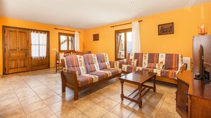 A living room with two sofas, a wooden coffee table, and a dining area with chairs.