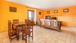 A dining area with a wooden table and chairs, a sofa, and a cabinet.