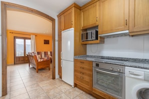 Une cuisine avec des meubles de rangement en bois, un réfrigérateur blanc, un four à micro-ondes, un four traditionnel et un lave-vaisselle.