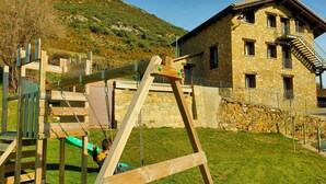 A wooden swing set and a stone building with a staircase.
