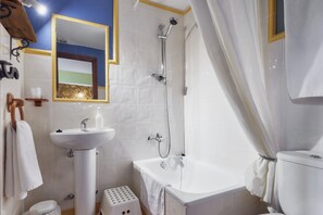Un baño con lavamanos, espejo, ducha, inodoro y un taburete pequeño.