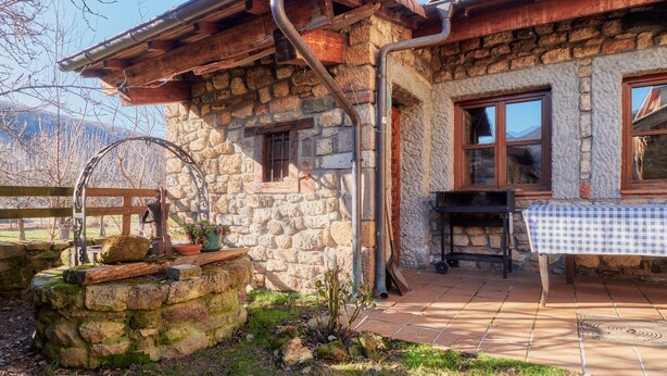 A stone building with a wooden porch, a table with a checkered tablecloth, and a rustic outdoor setting. - Country House 'Aldaron' with Mountain View, Private Garden and Wi-Fi (BOCA DE HUERGANO)