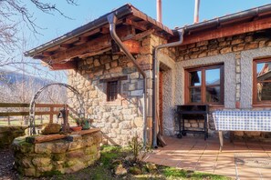 A stone building with a wooden porch, a table with a checkered tablecloth, and a rustic outdoor setting. - Country House 'Aldaron' with Mountain View, Private Garden and Wi-Fi (BOCA DE HUERGANO)