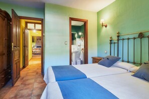Un dormitorio con cama, mesita de noche, espejo y puerta que da a un baño.