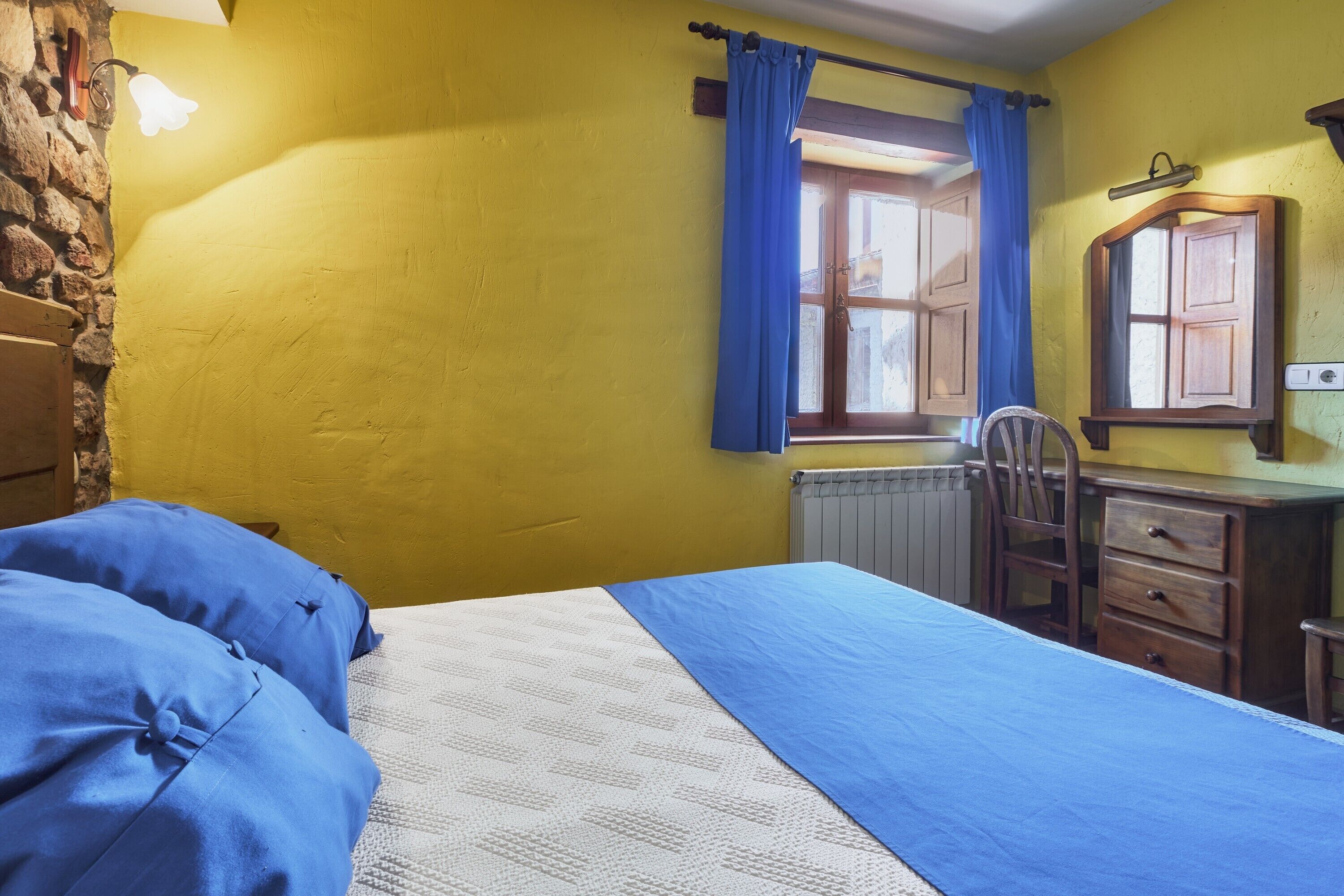 A bedroom with a bed, a dresser, a chair, and a window with curtains.