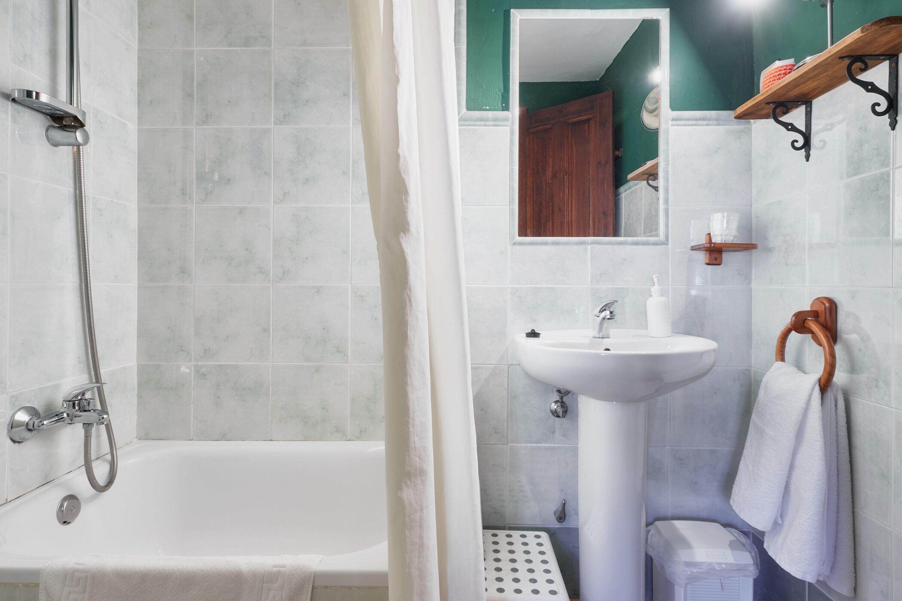 Un baño con bañera, lavamanos, espejo y ducha.