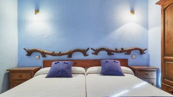 Una cama doble con dos mesitas de noche, cabecera de madera y lámparas fijadas a la pared.