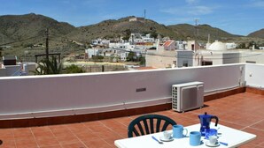 A terrace with a table set for two, overlooking a hillside village with white buildings and a hill in the background. - Country House 'Daniela 2' with Sea View, Wi-Fi and Air Conditioning (El Pozo de los Frailes)