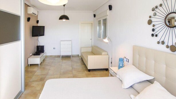 A hotel room with a large bed, a sofa, a TV, and a wall-mounted mirror. - Country House 'Daniela 2' with Sea View, Wi-Fi and Air Conditioning (El Pozo de los Frailes)