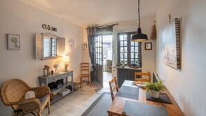 A dining area with a wooden table, chairs, a buffet, and a kitchen visible through an open door. - Cosy Duplex Apartment - Ardèche Riverside with Private Terrace, Balcony & Wi-Fi (Lanas)