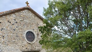 A stone building with a cross on top, a circular window, and a door. - Cosy Duplex Apartment - Ardèche Riverside with Private Terrace, Balcony & Wi-Fi (Lanas)